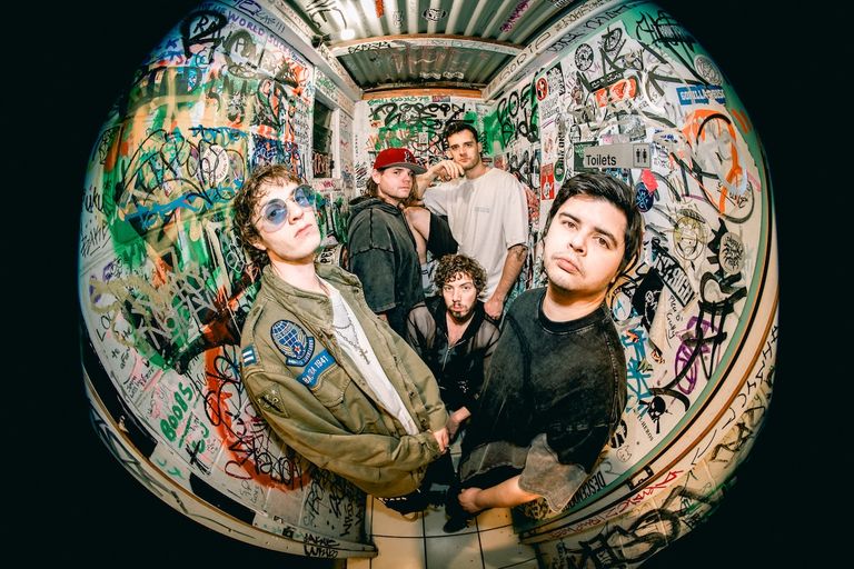 Fisheye lens promo shot of rock band Down And Out inside a venue hallway covered in graffiti and stickers.